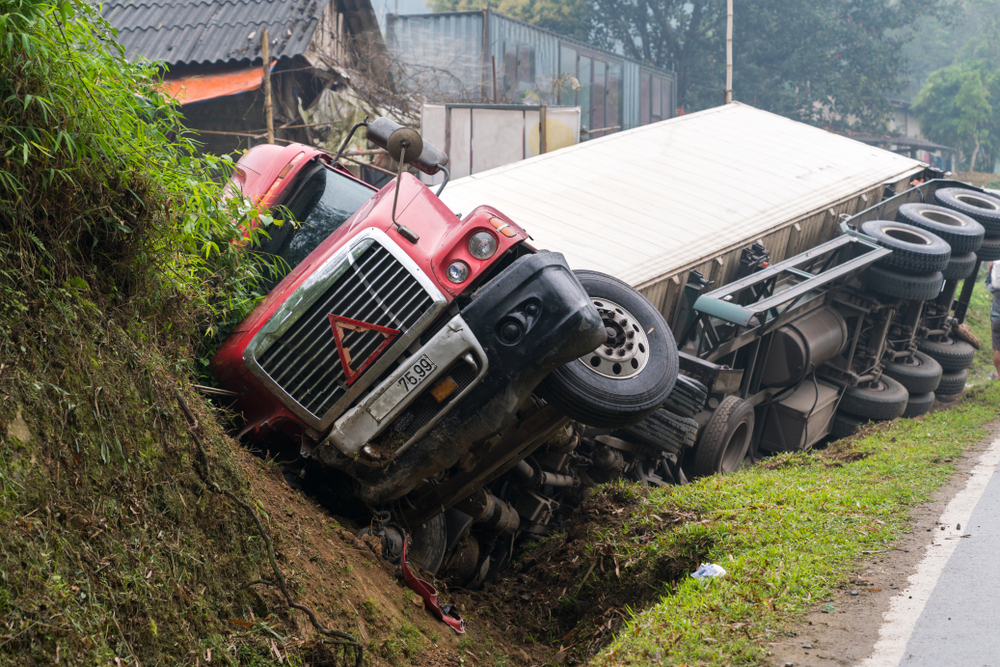 accident and urgency, set against a backdrop of a rural area with greenery and structures.